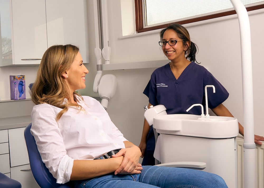 Dr Paroo Mistry, Consultant Orthodontist, chatting with a patient in the dental chair